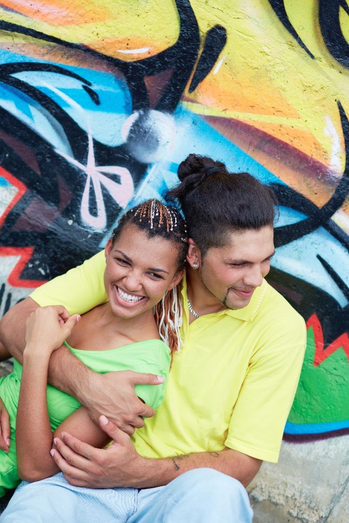 Image of young guy embracing his girlfriend on background of graffiti wall