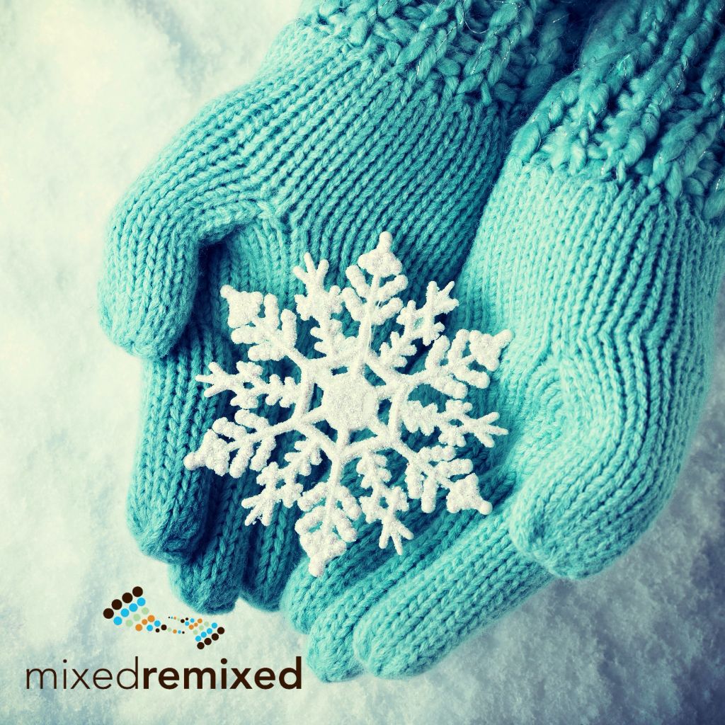 Female hands in light teal knitted mittens with sparkling wonderful snowflake on a white snow background. Winter and Christmas concept.